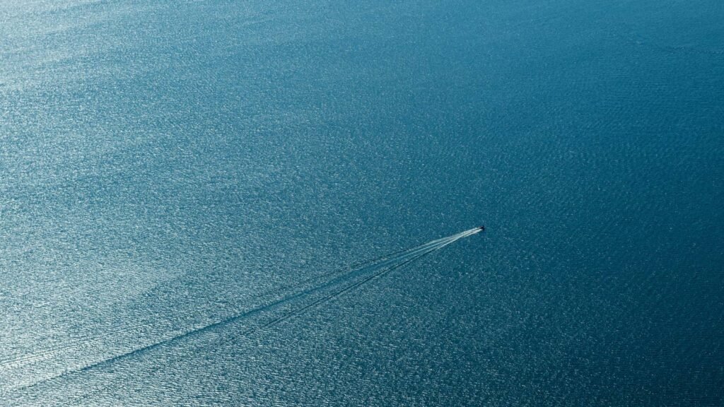 Die Weite des Meeres mit einer einzelnen Bootsspur – minimalistische Fotokunst für optische Tiefe in Räumen.