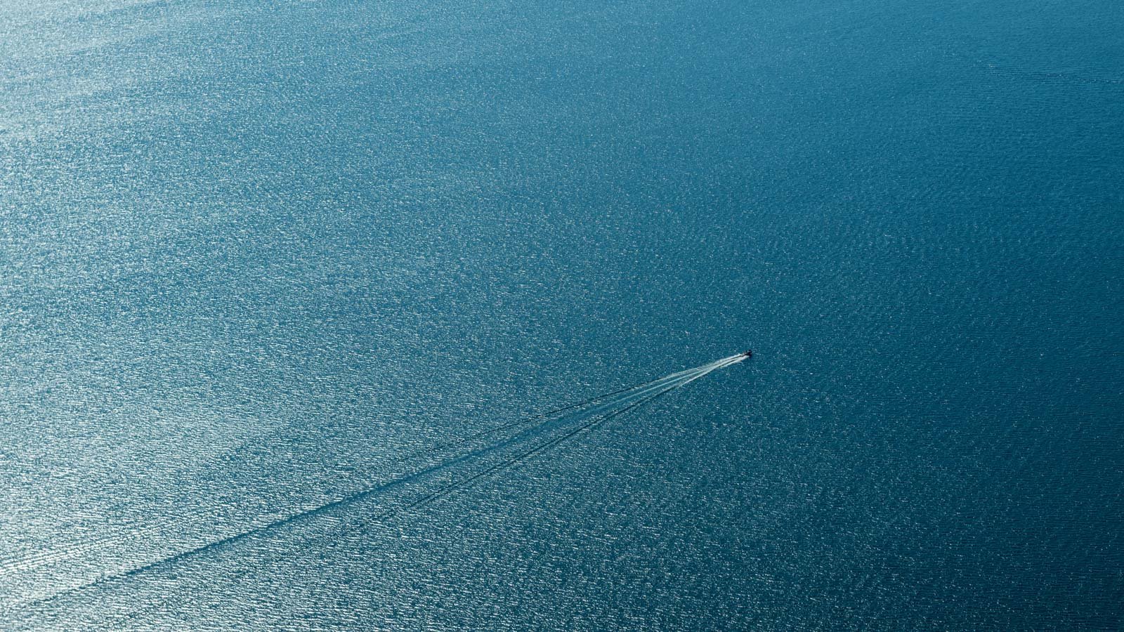 Die Weite des Meeres mit einer einzelnen Bootsspur – minimalistische Fotokunst für optische Tiefe in Räumen.