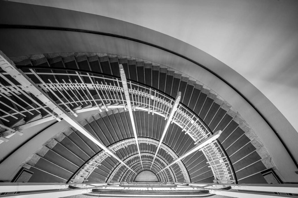 Künstlerische Schwarz-Weiß-Aufnahme einer Wendeltreppe aus der Vogelperspektive.